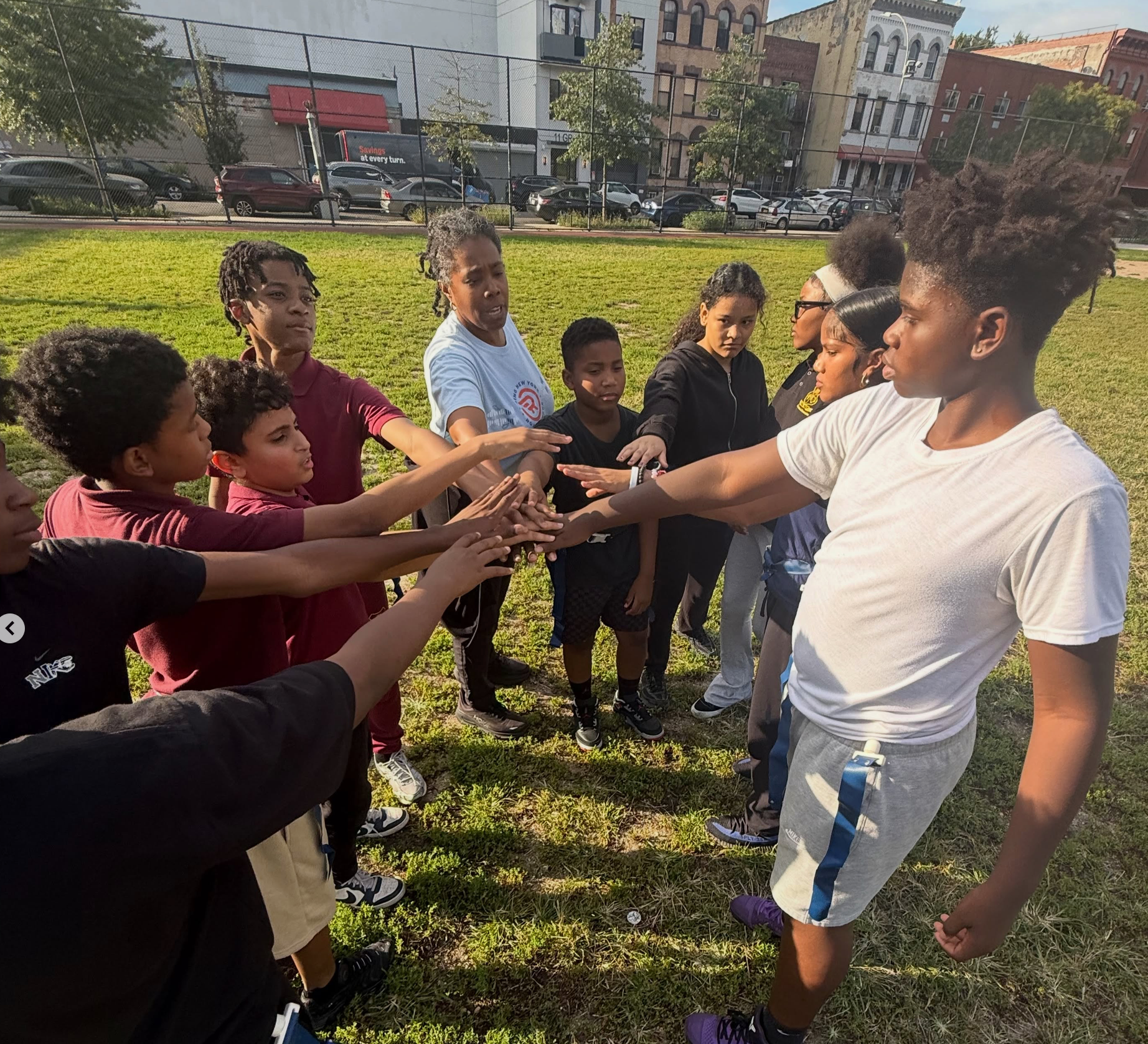 Scholars joining hands outdoors in a team huddle
